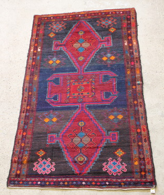 A blue and red ground Persian rug with medallions to the centre 85" x 51"