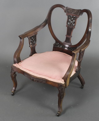 An Edwardian carved and pierced mahogany tub back armchair upholstered in pink dralon on cabriole supports 