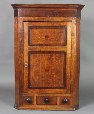 A Georgian oak corner cabinet with moulded cornice, fitted shelves enclosed by panelled doors, the base fitted 1 long and 2 dummy drawers 45"h x 31"w x 18"d 