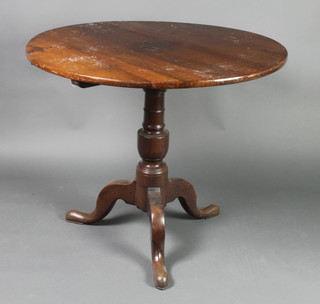 A 18th/19th Century circular oak snap top tea table, raised on a turned column and tripod base 27"h x 32" diam.  