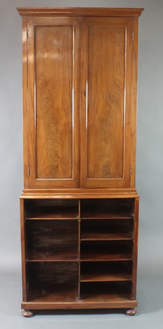 A Victorian mahogany cabinet on cabinet with moulded cornice, fitted shelves enclosed by panelled doors, the open base fitted shelves and raised on bun feet 83"h x 32"w x 17"d 
