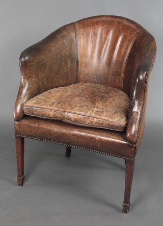 A tub back library chair upholstered in brown leather raised on square tapering supports 
