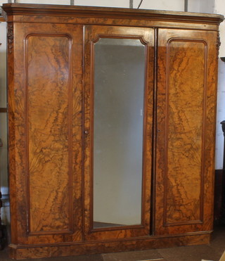 A Victorian figured walnut triple wardrobe with moulded cornice, the interior fitted a hanging space above 3 drawers, raised on a platform base, 85"h x 96"w x 25"d 