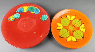 A Poole orange ground dish with floral decoration 5 14", a red ground ditto with free form decoration 16" 
