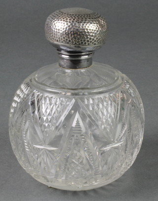 An Edwardian silver mounted spherical cut glass toilet bottle with hammer patterned lid 5" 