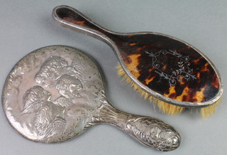 An Edwardian repousse silver Reynolds Angels hand mirror, a silver and tortoiseshell pique hair brush