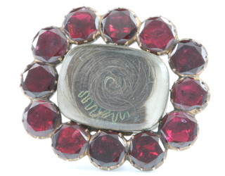 A 19th Century in memorium brooch, the centre hair locket surrounded by 12 brilliant cut garnets with inscription, dated 1838 
