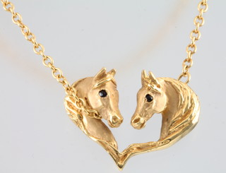 A 9ct yellow gold double horse head pendant with gem set eyes on a 14ct chain, 8 grams 