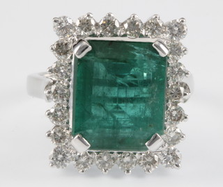 An 18ct white gold rectangular emerald and diamond ring, the central emerald 9.3ct surrounded by 22 brilliant cut diamonds, approx. 1.4ct, with certificate
