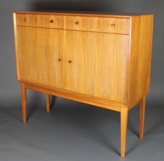 Gordon Russell, a 1950's mahogany and Indian laurel wood sideboard decorated circles and ellipses, designed by David Booth and Judith Ledeboer, comprising 2 drawers and cupboard doors, raised on square tapered legs 45"h x 48"w x 17"d 