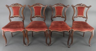 A set of 4 Victorian carved walnut dining chairs of serpentine outline, the seats and backs upholstered in pink dralon, raised on cabriole supports