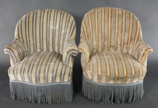 A pair of Victorian tub back armchairs, upholstered in striped material, raised on turned ebonised supports 