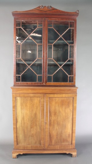 A 19th Century mahogany cabinet on cabinet, the upper section with moulded cornice, the interior fitted adjustable shelves enclosed by astragal glazed doors, the base fitted a cupboard enclosed by panelled doors, raised on bracket feet 80"h x 37"w x 16"d 