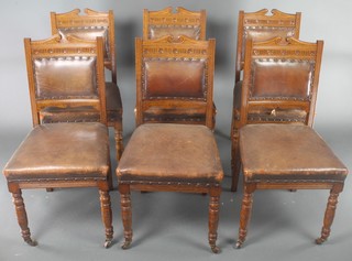 A set of 6 Edwardian carved oak dining chairs, the seats and backs upholstered in brown leather, raised on turned supports