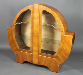 An Art Deco walnut circular shaped display cabinet, fitted shelves enclosed by a pair of panelled doors 50"h x 53"w x 12"d