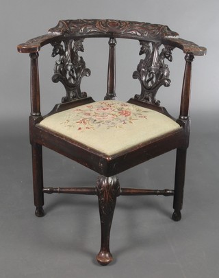 A 19th Century carved oak corner chair with pierced vase shaped slat back and drop in Berlin woolwork seat, raised on turned supports 