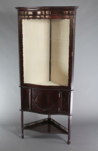 An Edwardian Chippendale style mahogany corner cabinet of serpentine outline, the interior fitted adjustable shelves enclosed by glazed panelled doors with under tier and pierced raised back, raised on square tapering supports, spade feet 72"h x 31"w x 18"d 