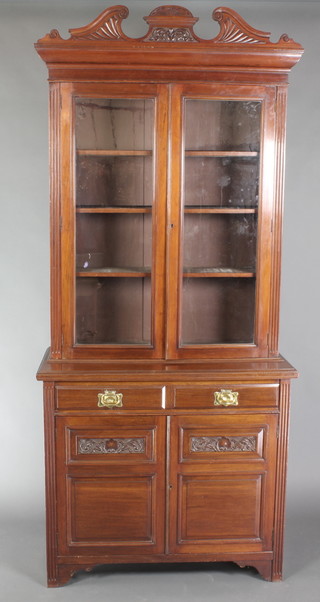 An Edwardian Art Nouveau mahogany bookcase on cabinet, the upper section with moulded cornice, fitted adjustable shelves enclosed by glazed panelled doors and having fluted columns to the sides, the base fitted 2 short drawers with brass plate drop handles above a double cupboard enclosed by panelled doors 92"h x 41"w x 18"d 