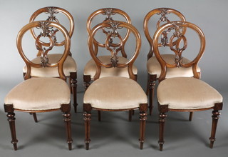 A set of 6 Victorian carved walnut balloon back dining chairs with over stuffed seats, raised on turned and fluted supports 