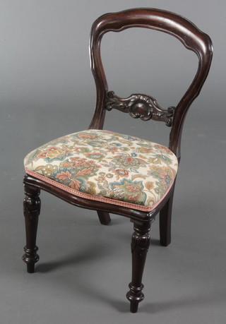 A Victorian buckle back childs chair with carved mid rail and upholstered seat of serpentine outline, raised on turned supports 