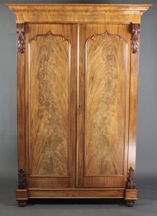 A Victorian Channel Islands mahogany press cabinet with moulded cornice, enclosed by arched panelled doors and with vitruvian scrolls to the side, raised on bun feet 89"h x 61"w x 27 1/2"d 