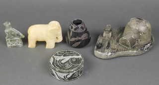 An Inuit carving in the form of a bird, the base marked PD 3 1/2", an Inuit carving of a figure by an igloo 8", a circular Inuit jar and cover 4", a carved vase decorated fish 3" and a carved hardstone figure of an elephant 3" 