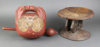 A circular carved "African" stool raised on 4 shaped supports with rounded base 7"h x 9" diam. together with a Chinese red painted carved wooden bell with beater 
