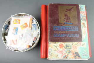 A Windsor stamp album of various used GB stamps, a Global Master stamp album of various used world stamps, a Welcome illustrated stamp album together with a circular tin of loose stamps 