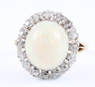 An 18ct yellow gold opal and diamond cluster ring, the centre cabuchon cut stone approx. 4ct surrounded by 16 brilliant cut diamonds, approx .45ct, size L 