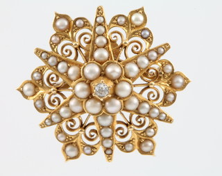 An 18ct yellow gold open scroll seed pearl and diamond set star brooch, the centre diamond approx. 0.10ct,with a 9ct gold pin, gross 12 grams