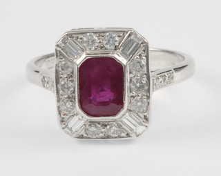 An 18ct white gold ruby and diamond Art Deco style up finger ring, the centre emerald cut stone approx. 0.75ct, surrounded by 4 baguettes and 10 brilliant cut diamonds, the shank with 3 diamonds to each shoulder, size N 1/2
