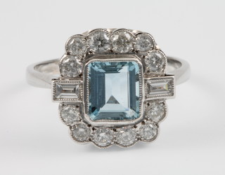 An 18ct white gold aquamarine and diamond up finger ring, the centre emerald cut stone approx. 1ct flanked by 2 baguette diamonds and 12 brilliant cut diamonds, size P