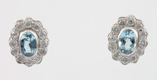 A pair of 18ct white gold oval aquamarine and diamond cluster ear studs, the centre stone each approx. 0.4ct, surrounded by brilliant cut diamonds