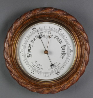 An aneroid barometer with silvered dial contained in a carved oak rope edge case 10" 