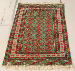 A green ground Bokhara rug with 30 octagons to the centre within a multi row border 24" x 49" 