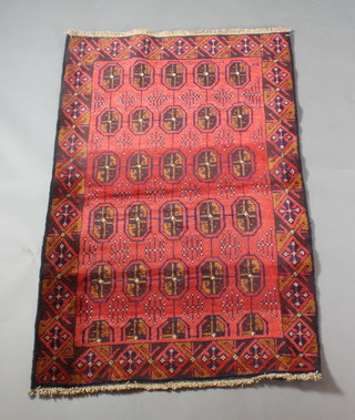 A red ground Persian Belouch rug with 30 stylised octagons to the centre 56" x 35"