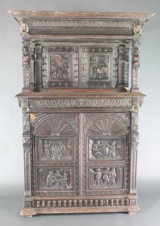 A Victorian carved oak cabinet on cabinet, the upper section with moulded and carved cornice, fitted a cupboard enclosed by a pair of panelled doors decorated tavern scenes above 1 long drawer, the base enclosed by carved arched panelled doors decorated tavern scenes, heavily carved throughout 69"h x 46"w x 19"d