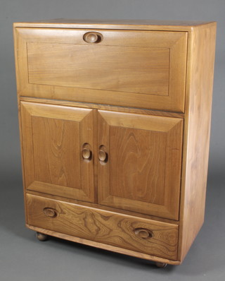 An Ercol light elm bureau/cocktail cabinet, the fall front revealing a shelved interior above a cupboard enclosed by panelled doors, the base fitted 1 long drawer, the interior of the cupboard marked RD 905.094on castors 43"h x 32"w x 17"d 
