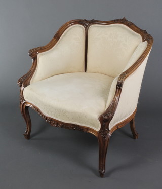 A Victorian carved walnut show frame tub back chair upholstered in cream material, raised on cabriole supports 