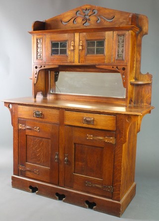 An Arts & Crafts oak sideboard with pierced raised back fitted a cupboard enclosed by lead glazed panelled doors and having embossed copper panels to the side above a mirrored back recess, the base fitted 2 long drawers above double cupboard enclosed by panelled doors with copper handles, raised on a platform base 69"h x 60"w x 22"w 