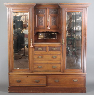 A Victorian carved walnut inverted breakfront wardrobe with moulded and dentil cornice, the centre section fitted a cupboard enclosed by a glazed panelled door above a recess with mirrored panel above 2 short and 2 long drawers, flanked by a pair of cupboards enclosed by mirror panelled doors, the base fitted 2 long drawers, raised on a platform base 79"h x 73 1/2"w x 20 1/2"d 