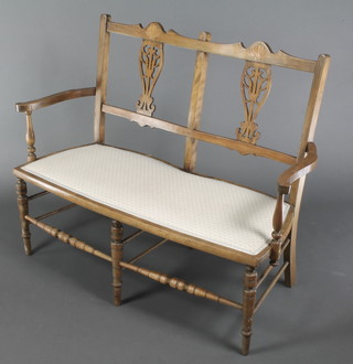 An Edwardian inlaid and bleached mahogany double chair back settee with vase shaped slat back, raised on turned supports with stretcher 