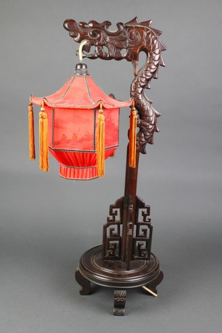 A 1930's Chinese carved and pierced hardwood table lamp in the form of a dragon raised on a circular base with printed landscape shade 27"h x 8" diam. 