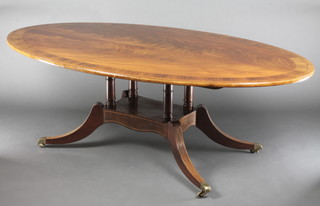 A Georgian style oval mahogany dining table with crossbanded and inlaid top, raised on 4 turned columns and platform base ending in splayed feet, brass caps and casters 28"h x 85 1/2"l x 48"w 