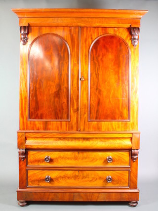 A Victorian mahogany linen press with moulded cornice enclosed by arched panelled doors the base fitted a secret drawer above 2 long drawers with tore handles, raised on bun feet 88"h x 59"w x 24"d 