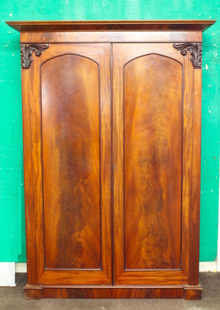 A Victorian Channel Islands mahogany knock down wardrobe with moulded cornice, the interior fitted a tray and hanging space enclosed by a pair of arch panelled doors, raised on a platform base 83"h x 59"w x 23 1/2"d 