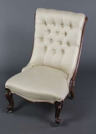 A Victorian mahogany show frame nursing chair, upholstered in cream coloured buttoned back material, raised on cabriole supports
