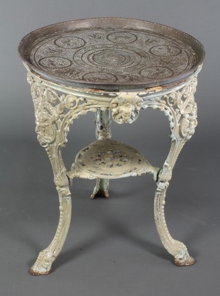 A pierced cast iron pub table with under tier, raised on out swept supports with an associated Benares brass top 27"h x 22" diam. 