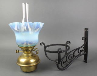 A 19th Century brass oil lamp with blue vaseline glass shade (chip to edge) together with a wrought iron bracket