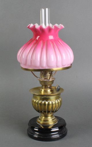A Victorian reeded brass oil lamp reservoir with clear chimney and pink opaque glass shade 